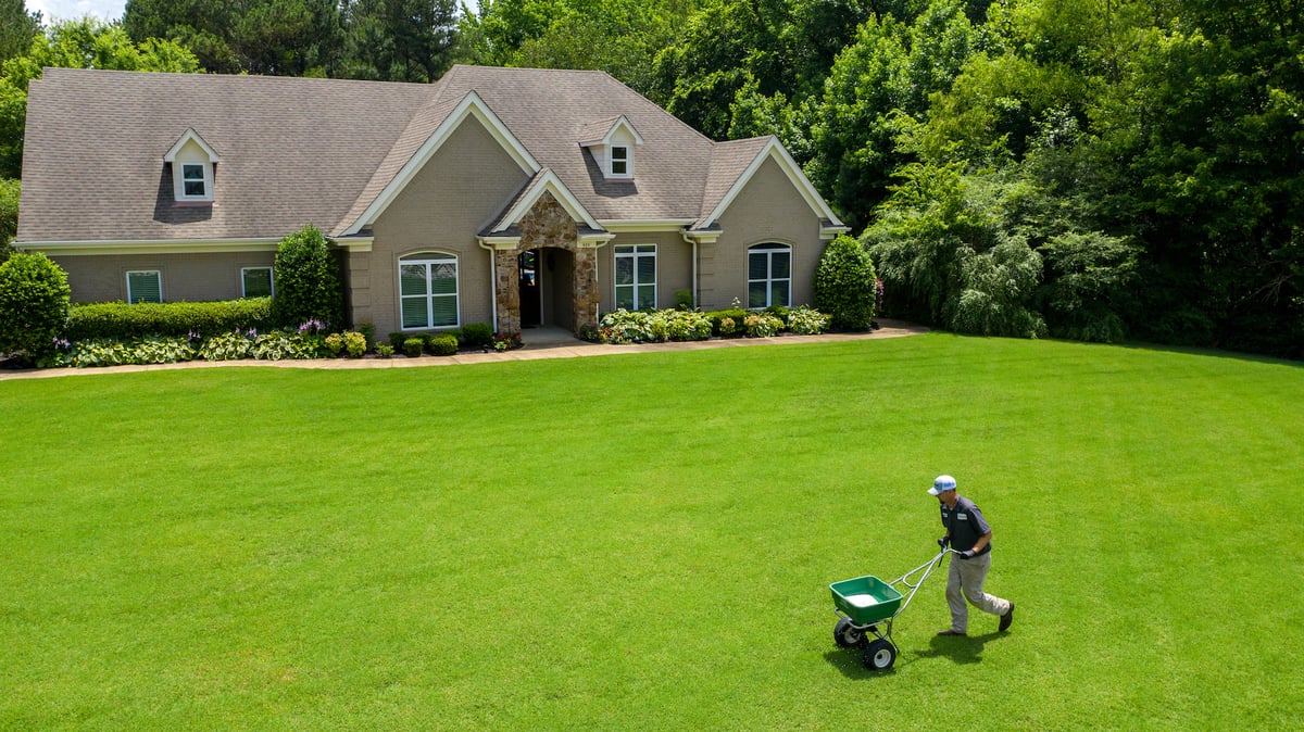 lawn care technician spreading fertilizer