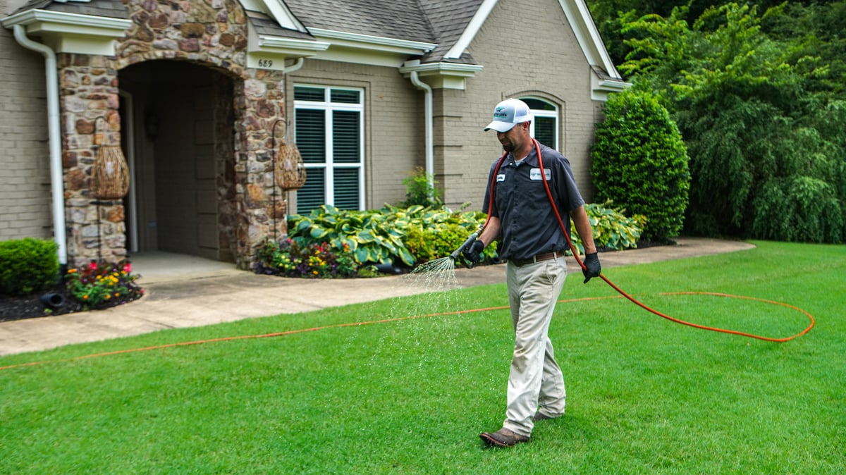 lawn care technician spraying grass for weeds