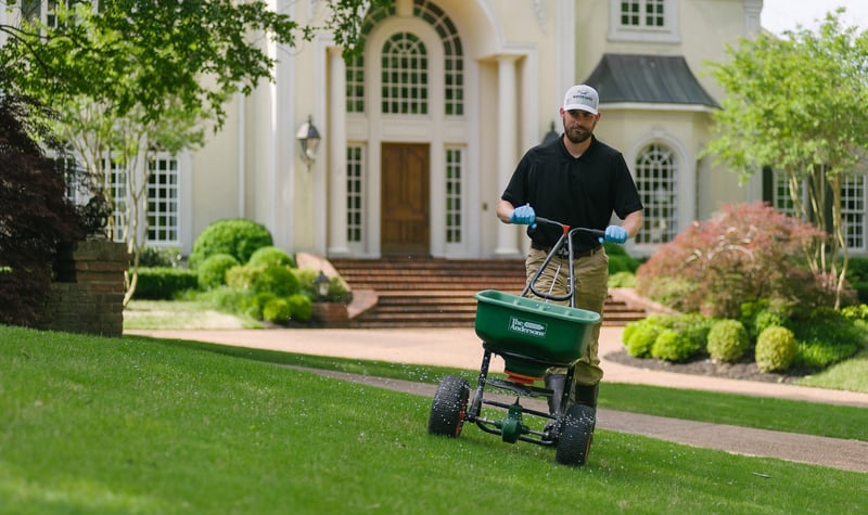 lawn care technician fertilizing lawn