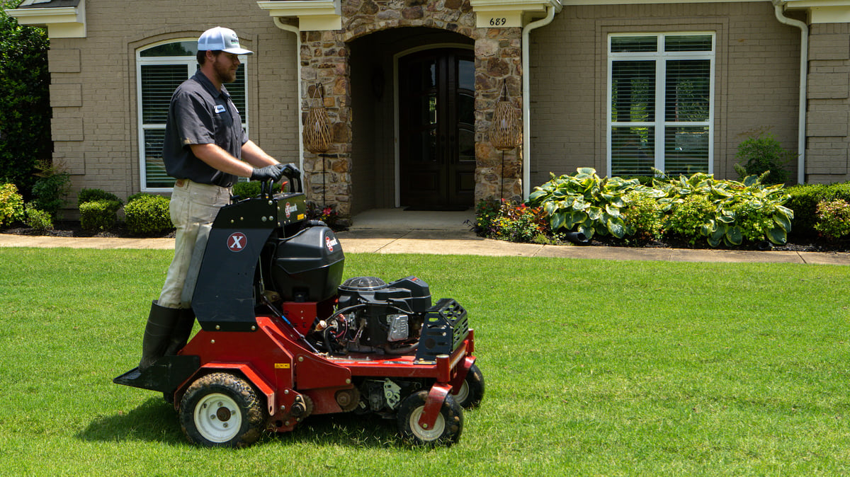 technician performs lawn aeration with ride on aerator