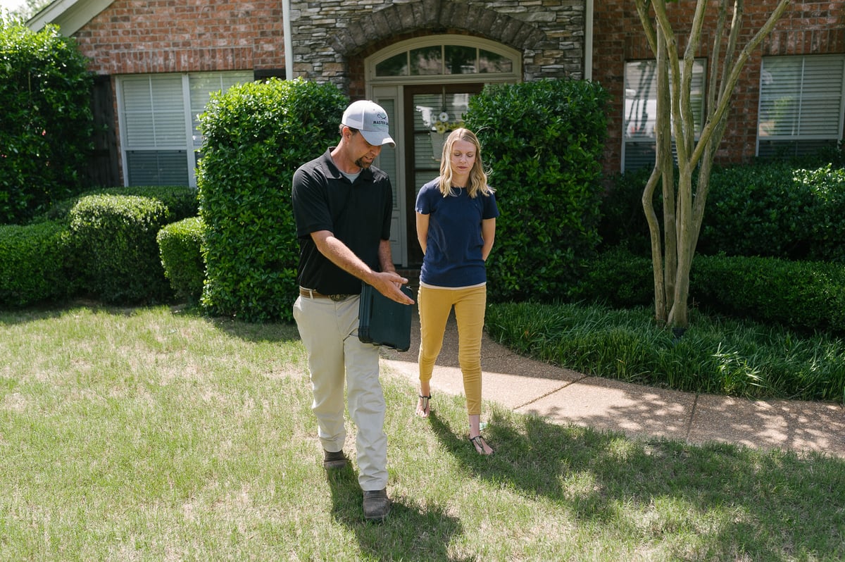 lawn care technician talks with homeowner about lawn